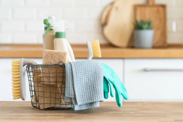 Photo of Basket with brushes, rags, natural sponges and cleaning products.