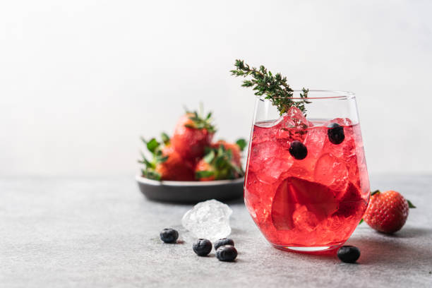 Summer refreshing drink Pink drink with crushed ice and thyme. Strawberry and blueberry lemonade pink tea stock pictures, royalty-free photos & images