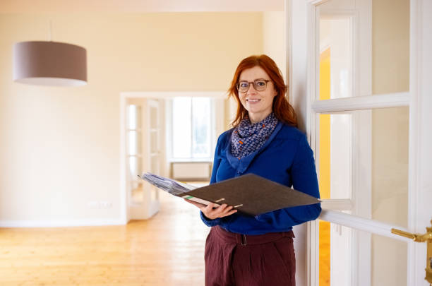 istock Smiling redhead woman smiling while holding new home documents 1315341541