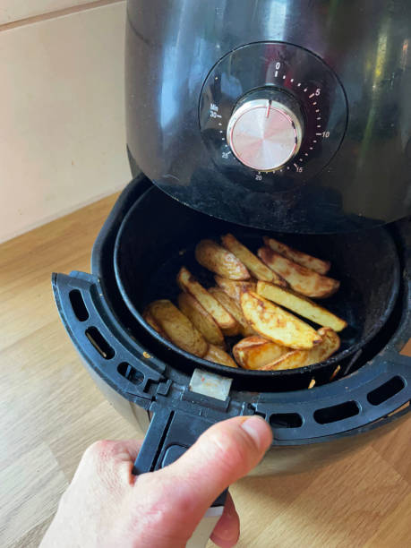 istock Image of unrecognisable person's hand pulling out pan from air fryer containing golden brown, fresh crunchy French fries / chunky chips, healthier alternative to snack cooking, elevated view 1315342099