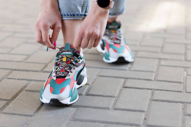 Female hand tying laces on multicolored sneakers closeup. Comfortable shoes concept