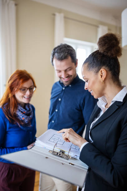 Real Estate Agent and customers discussing over blueprint