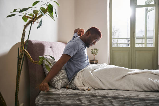 istock Man sitting at the bed and stretching while waking up on comfortable bed 1315345751
