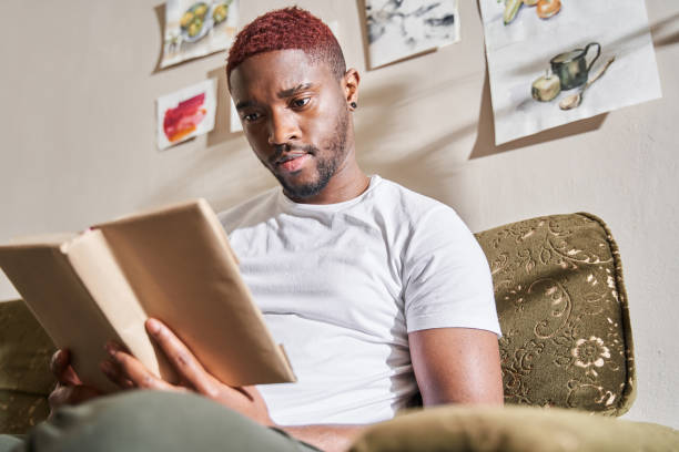 istock Man relaxing on sofa at home while reading his favorite book 1315345841