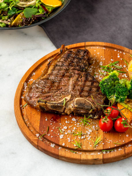 istock Medium rare Grilled T-Bone Steak with potato wedges, broccoli and wine on serving board block on dark background 1315346399