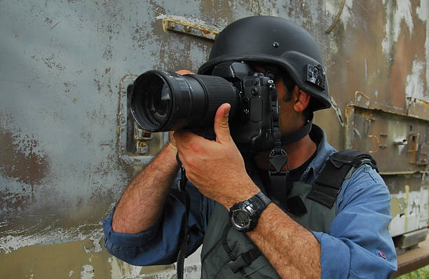 Press Photojournalist Photographer A press photojournalist is holding a camera with a zoom lens and is photographing war and conflict. east photos stock pictures, royalty-free photos & images