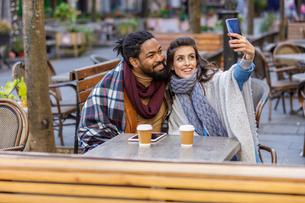 istock A Young Multi-Ethnic Couple is Spending a Wonderful Evening Together, Having a Lovely Communication and Sharing a Fresh Drink, and Taking Selfie Photos with Mobile Phone. 1315348367