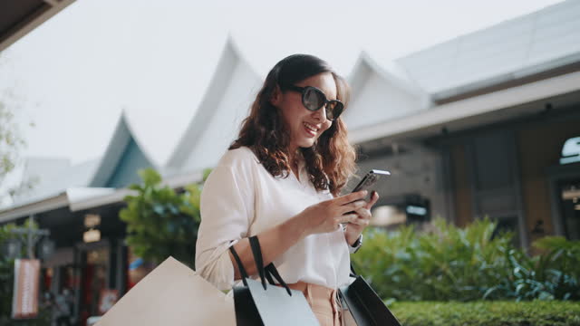 Woman using phone walking with Shopping bag
