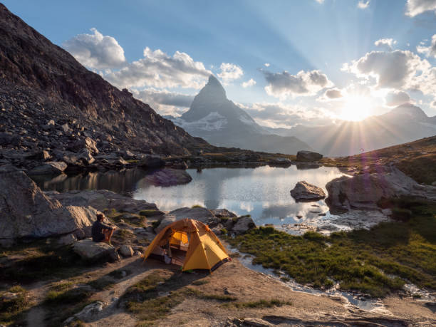 istock Man camping near alpine lake, sunset 1315352584