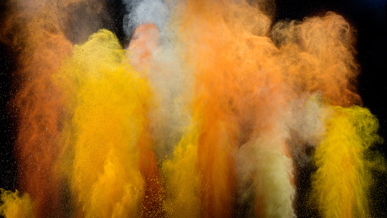 Colourful spices exploding into the air against black background.