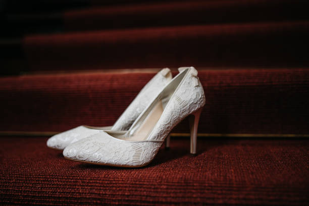 White bridal shoes with bows standing on red carpeted stairs White bridal shoes with bows standing on red carpeted stairs wedding shoes stock pictures, royalty-free photos & images