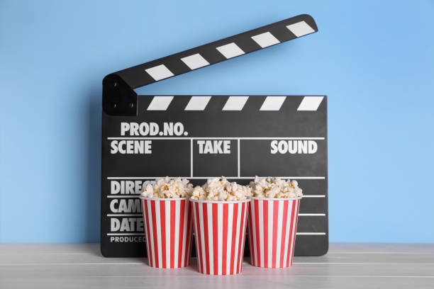 istock Delicious popcorn and clapperboard on light wooden table 1315358675