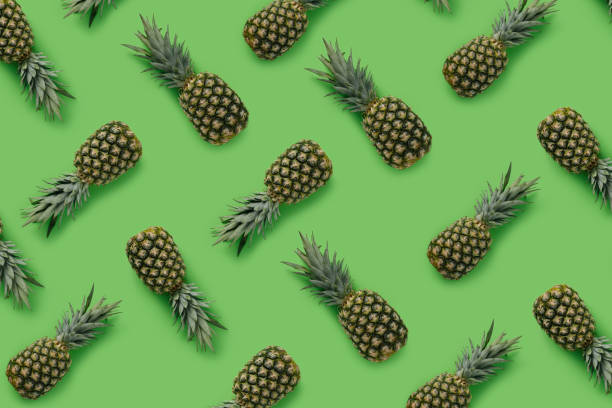 istock Fruit pattern with pineapples on green background. Minimal tropical food concept. Vegetarian vitamin diet trend. Exotic fruit texture. Flat lay, top view. 1315361673