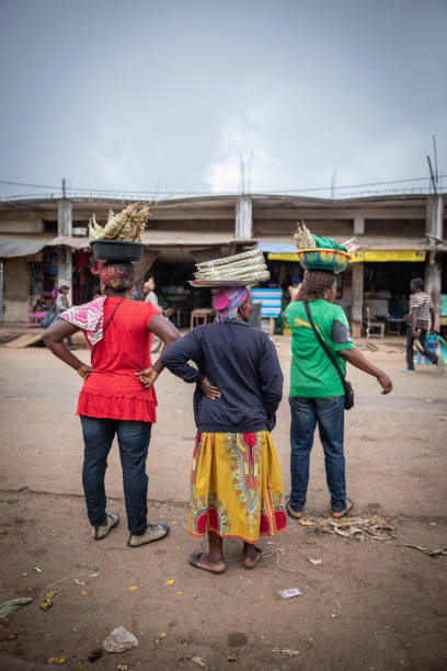 African women work with baskets of food resting on their heads African women working on the street selling traditional cameroonian food called bobolo and miondo. yaounde photos stock pictures, royalty-free photos & images