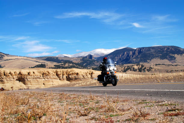 Lonetree, USA - July 24, 2019: Barren dry desert canyon landscape in Wyoming highway 414 road with bikers on Harley Davidson motorcycles bikes