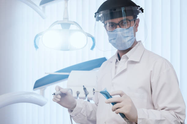 Male dentist is looking to camera from his dentist's office.
