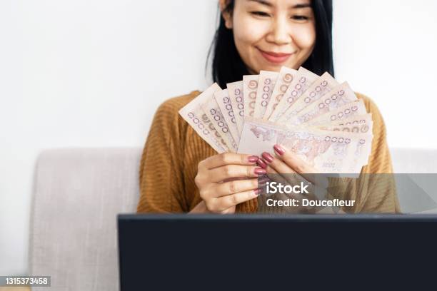 Asian Business Woman Hand Holding Thai Baht Banknotes Sitting On Sofa Successful With Make Money Online Stock Photo - Download Image Now