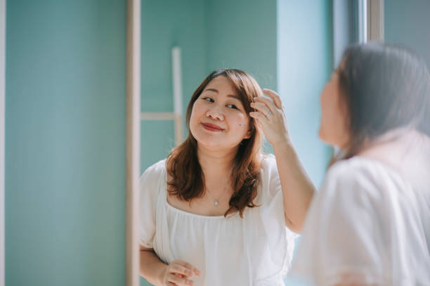 asiatico cinese corpo donna positiva godendo il suo fine settimana a casa trucco davanti allo specchio - foundation bed foto e immagini stock