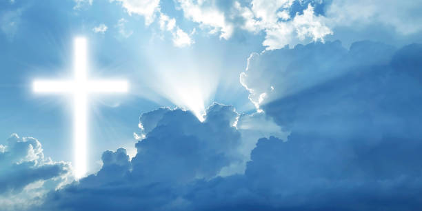 istock White shining Christian cross in the blue cloudy sky 1315374807