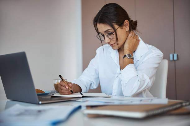 istock Beautiful woman writing in notebook and using laptop at work 1315374841