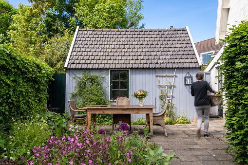 Typical Dutch house with senior woman walking in the small garden