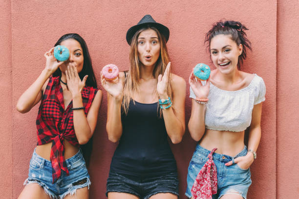 istock Attractive women making funny faces with colorful donuts 1315376638