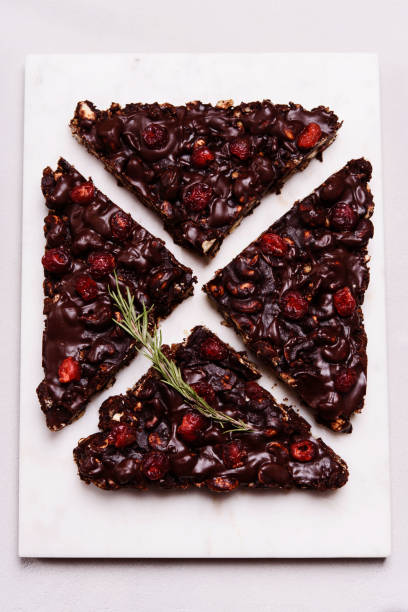 Mosaic Chocolate and Biscuit Cake with Nuts and Dried Cherries on white marble board. Chocolate and cookie dessert. Christmas delicious treat