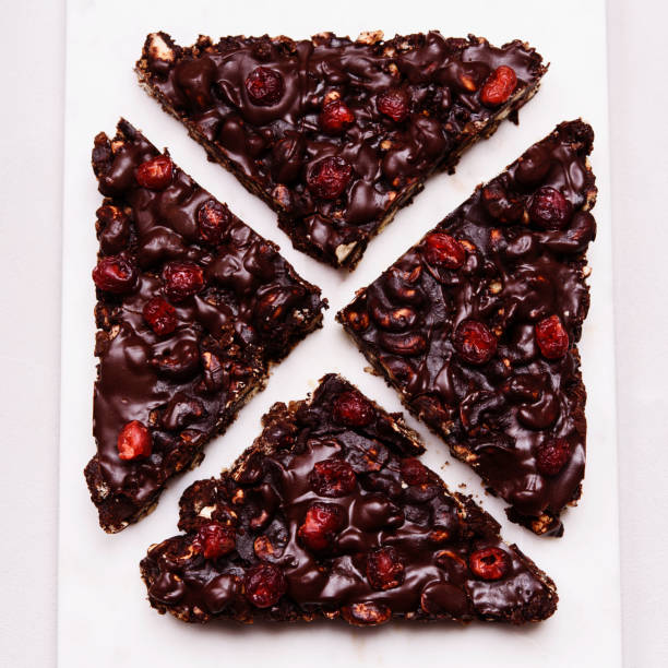 istock Mosaic Chocolate and Biscuit Cake with Nuts and Dried Cherries on white marble board. Chocolate and cookie dessert. Christmas delicious treat 1315376737