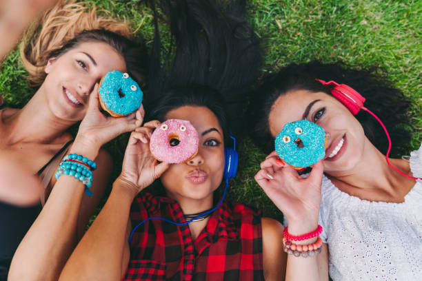 istock Attractive women making funny faces with colorful donuts 1315376771