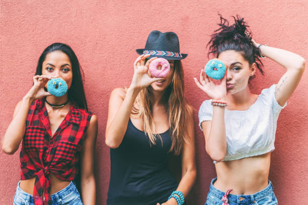 istock Attractive women making funny faces with colorful donuts 1315376827