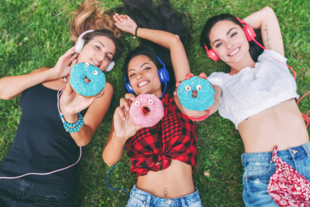 istock Attractive women making funny faces with colorful donuts 1315376942