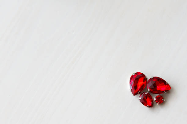 Red stones crystals beads of different sizes on a white wooden background in the corner