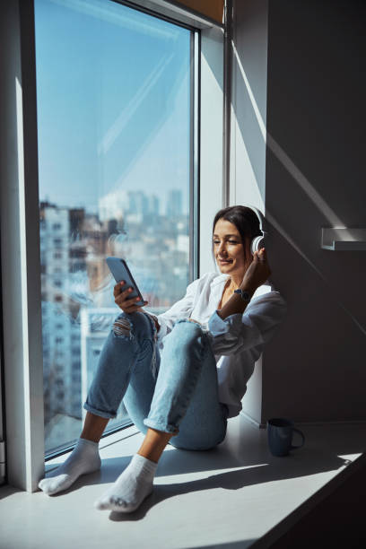 istock Charming woman in headphones using smartphone at home 1315382672