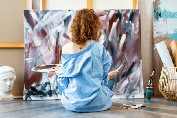 istock Woman artist is drawing sitting at floor in workshop studio 1315385707