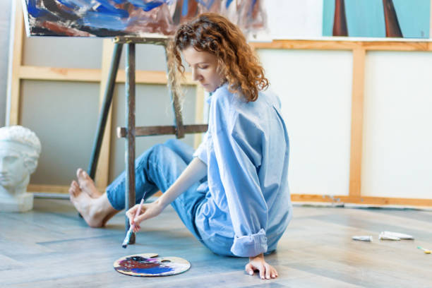 istock Woman artist is drawing sitting at floor in workshop studio 1315386445
