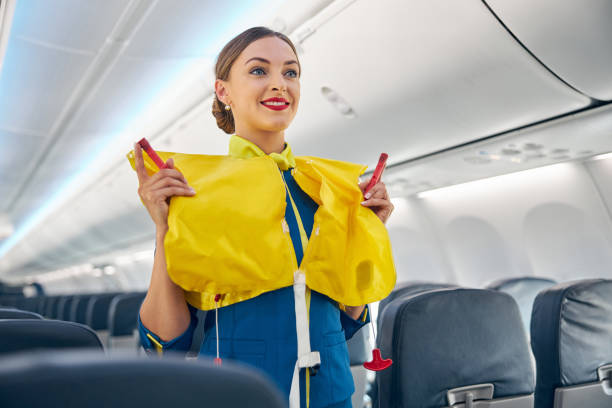 Flight attendant on board an airplane holding life jacket before flight procedure Stewardess in the cabin of the passenger airplane doing training of instruction on safety measures in the event of an emergency before the flight cabin crew stock pictures, royalty-free photos & images