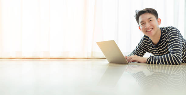 happiness peaceful smile asian male enjoy work from home quarantine relax and positive work with laptop,asian male attractive smart freelance lay down use laptop on laminate wooden floor felicidad sonrisa pacífica hombre asiático disfrutar del trabajo desde la cuarentena del hogar relajarse y trabajo positivo con el ordenador portátil, hombre asiático atractivo inteligente freelance establecer el uso de portátil en suelo de madera lam