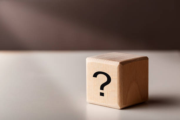 istock Wooden cubes with question mark in ray of light. FAQ concept 1315391117