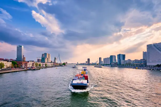 View of Rotterdam cityscape and Erasmus bridge over Nieuwe Maas with cargo ships and boats. Rotterdam, Netherlands