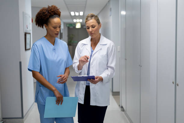 istock Two diverse female doctors standing in hospital corridor looking at medical chart document 1315401647