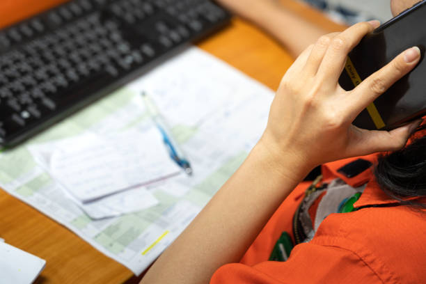 Talking on the duty mobile phone action, recieving an emergency report. Action of a safety officer is talking on the duty mobile phone, recieving an emergency report. With blurred of paper document for taking note on the table. Close-up and selective focus at people hand. emergency response workplace stock pictures, royalty-free photos & images