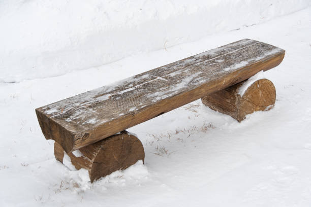 Alone wooden bench in winter park. Seat without back in snow