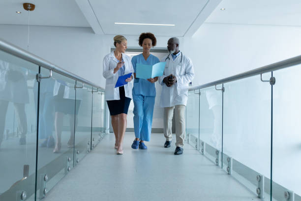 istock Three diverse male and female doctors walking through hospital corridor looking at document 1315403478