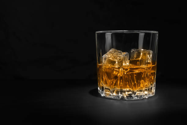 zbliżenie szklanki z napojem alkoholowym z lodem na czarnym tle. - whisky glass ice cube alcohol zdjęcia i obrazy z banku zdjęć