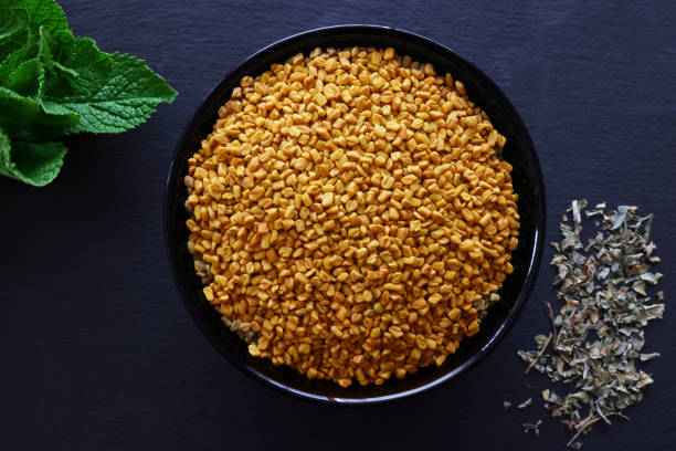 Fenugreek Seeds Fenugreek Seeds and Leaves on a black slate platter with copy space available fenugreek stock pictures, royalty-free photos & images