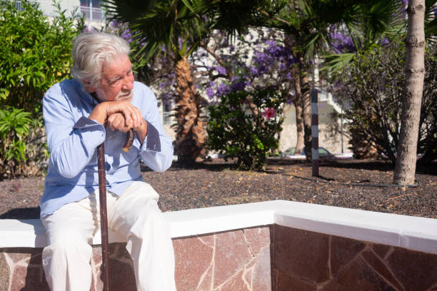 istock Suffering sad senior man sitting outdoors using a stick for legs pain 1315410798