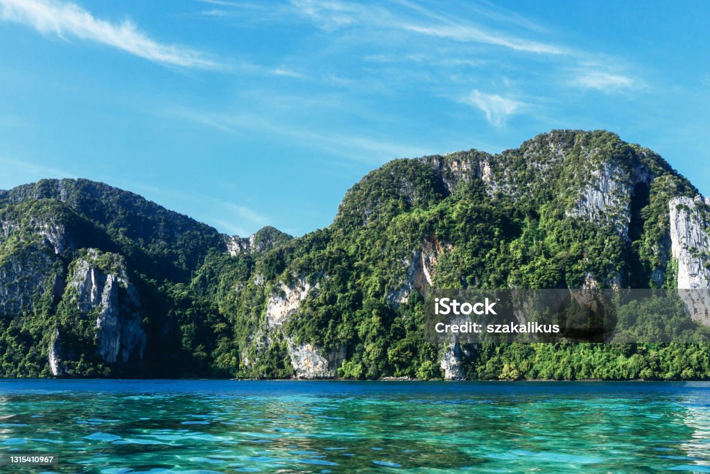 Sunny bay in Thailand. Lime stone high cliffs. Beautiful mountain area view from water. Tropical exotic holiday landscape. Boat trip around Ko Phi Phi island. Asia Stock Photo