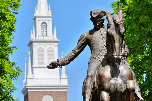 Paul Revere statue in Boston Freedom Trail, a national landmark and major tourist attraction. Old North Church steeple in the back.