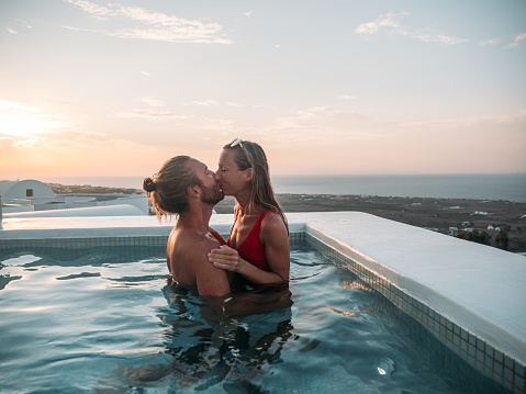 Romantic couple kissing at sunset in a hot tub