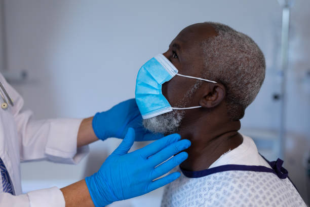 kaukaska kobieta lekarz palpating węzłów chłonnych afroamerykańskiego pacjenta płci męskiej w masce - lymph node zdjęcia i obrazy z banku zdjęć